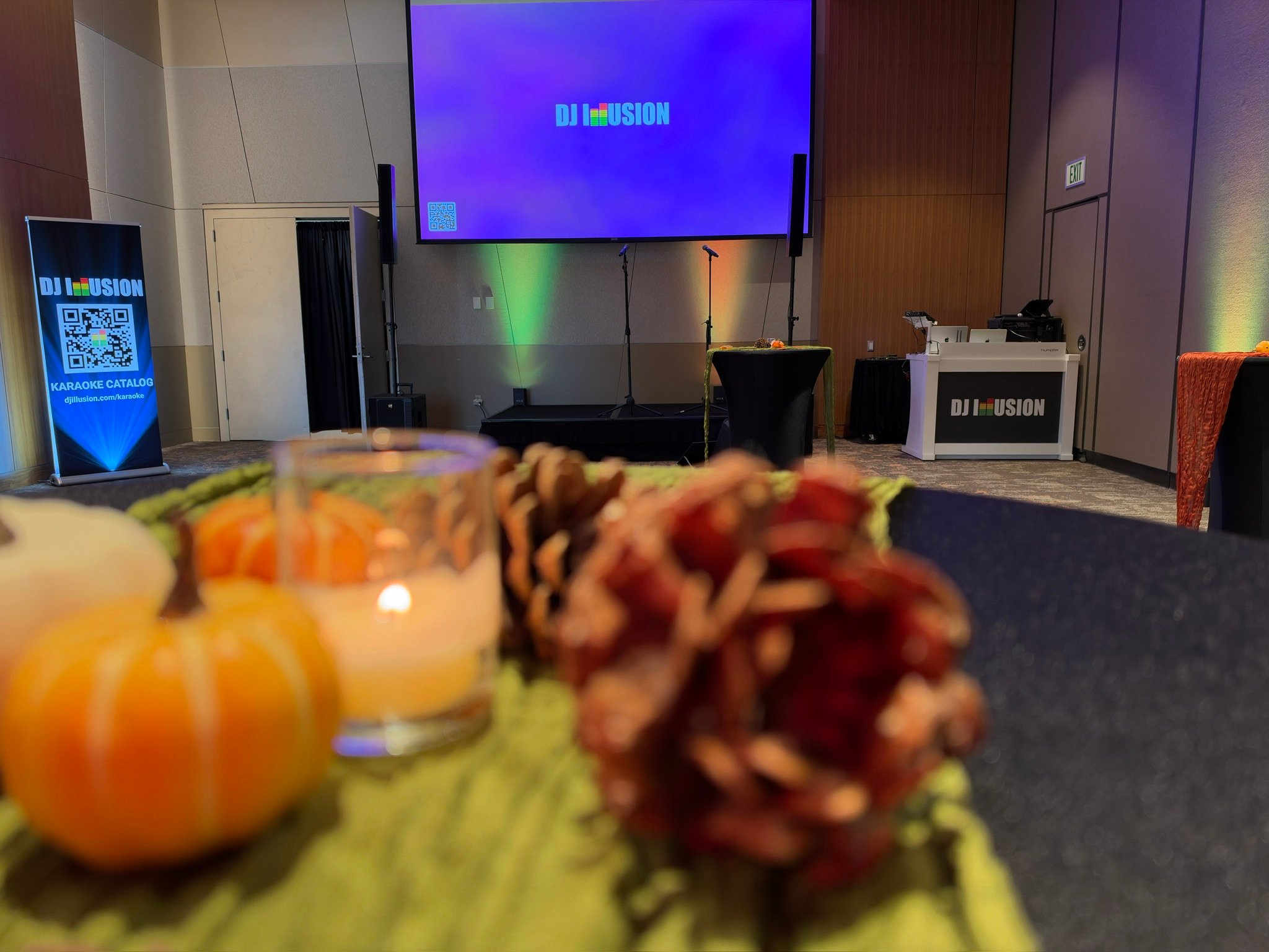 Hosted karaoke setup with two microphones, a lyrics screen, uplights, and the DJ Illusion booth