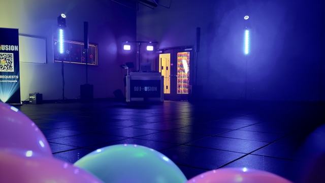 DJ Illusion glow dance setup with UV black lights and neon balloons in school gymnasium