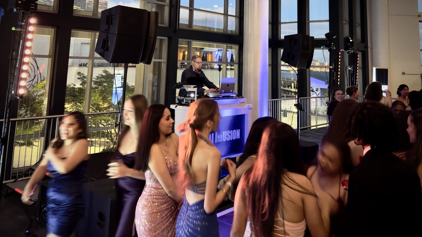 DJ Illusion setup at school TOLO or spring fling in elegant ballroom with blue uplighting and students